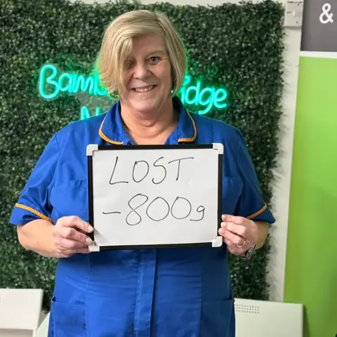Inside the club, a member displays her assessment results on a whiteboard