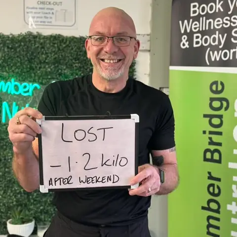 Smiling member at the club showing his results written up on the board